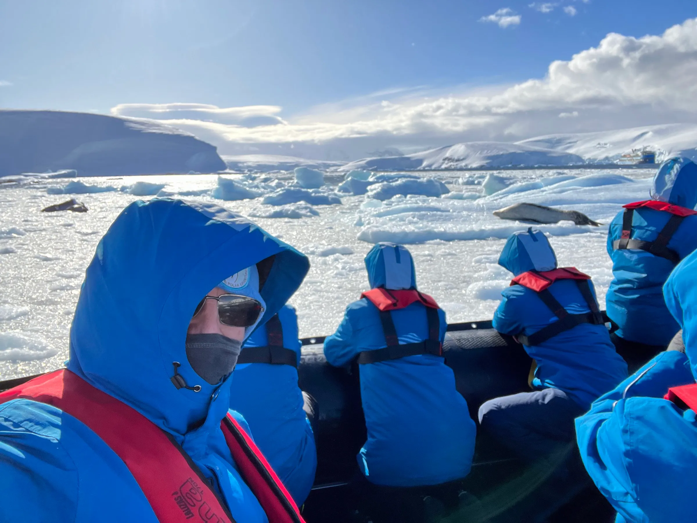 Andrew in a zodiac among sea ice in Antarctica, a leopard seal on the floe ahead